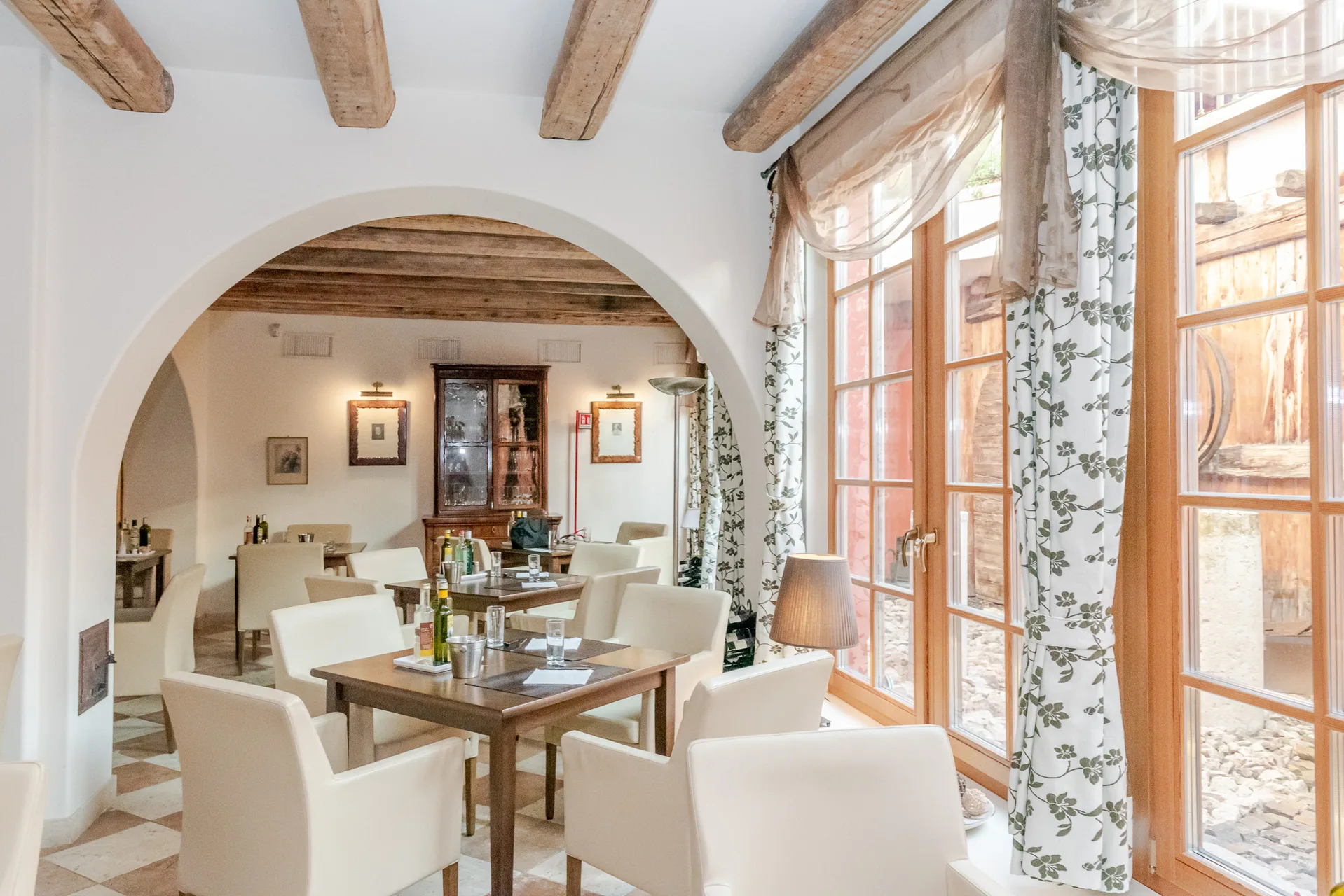 Sala ristorante con arco, tavoli e ampie finestre luminose