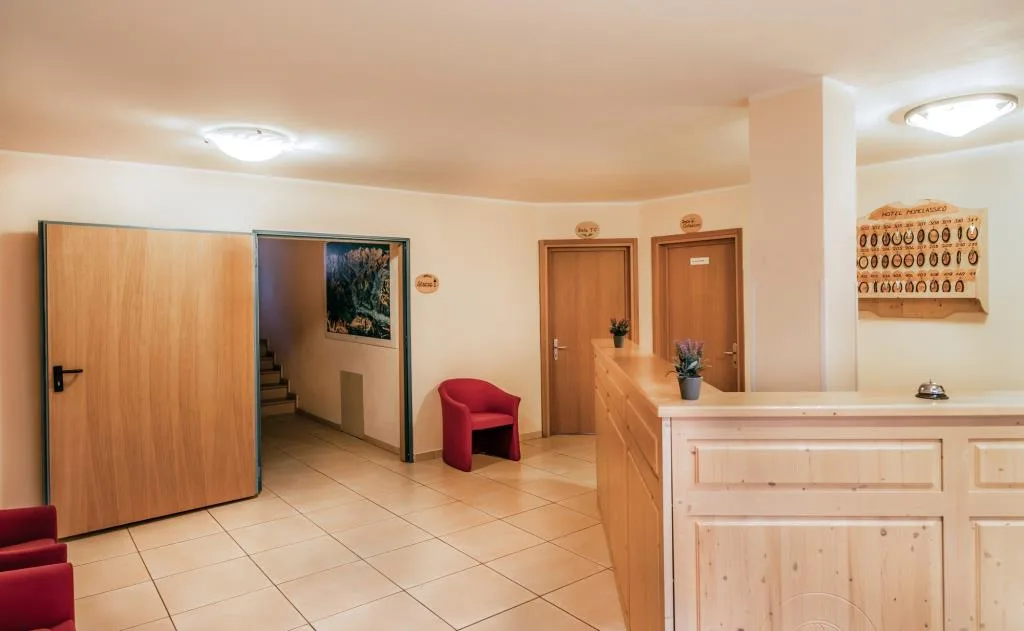 Reception dell'hotel con bancone in legno e poltrona rossa