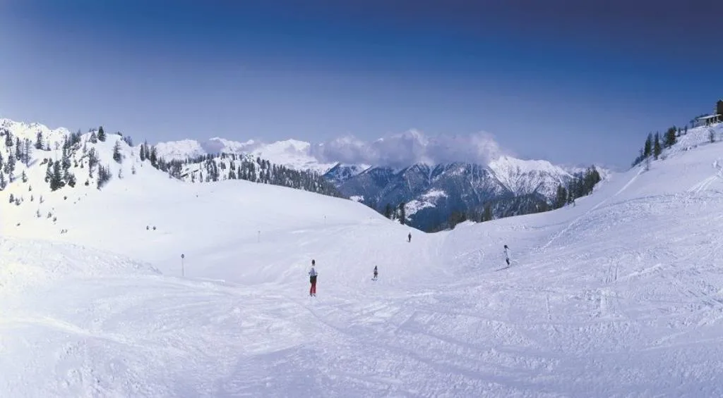 Panorama di pista da sci innevata con sciatori e montagne sullo sfondo