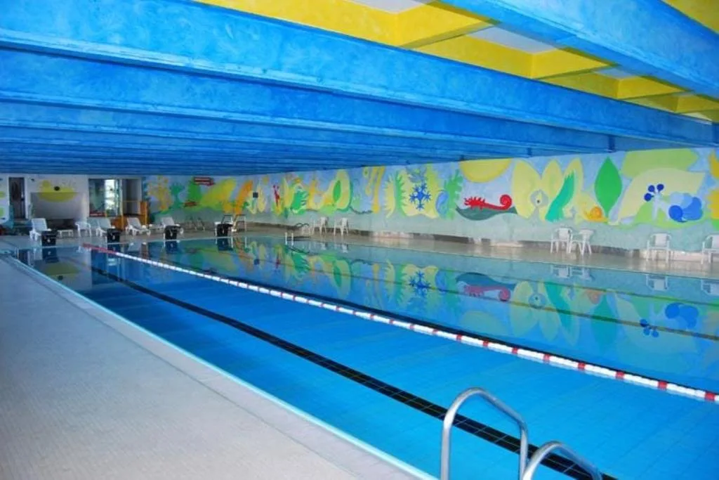 Piscina coperta con decorazioni colorate alle pareti e acqua azzurra