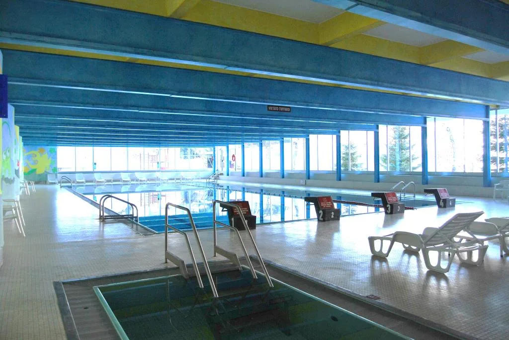 Piscina interna con corsie, lettini e grandi finestre sul paesaggio innevato