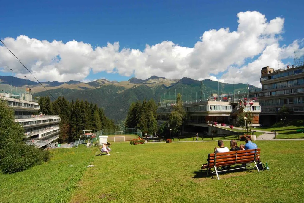 Prato estivo del resort con persone su una panchina e vista sulle montagne