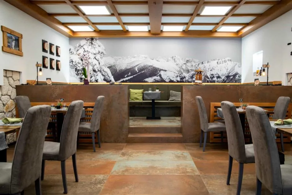 Sala ristorante moderna con sedie grigie e murale panoramico di montagne innevate