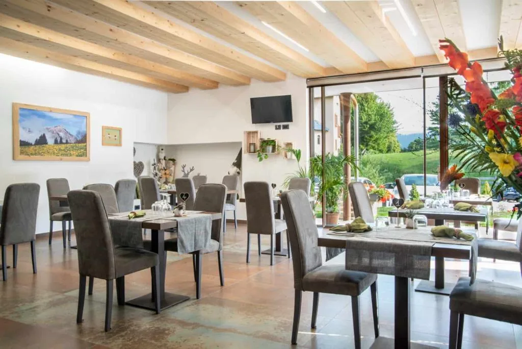 Ristorante con vetrata affacciata sul verde, TV e composizione floreale colorata