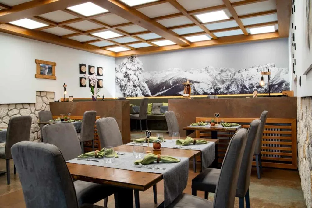 Sala ristorante elegante con parete in pietra e murale di montagne innevate