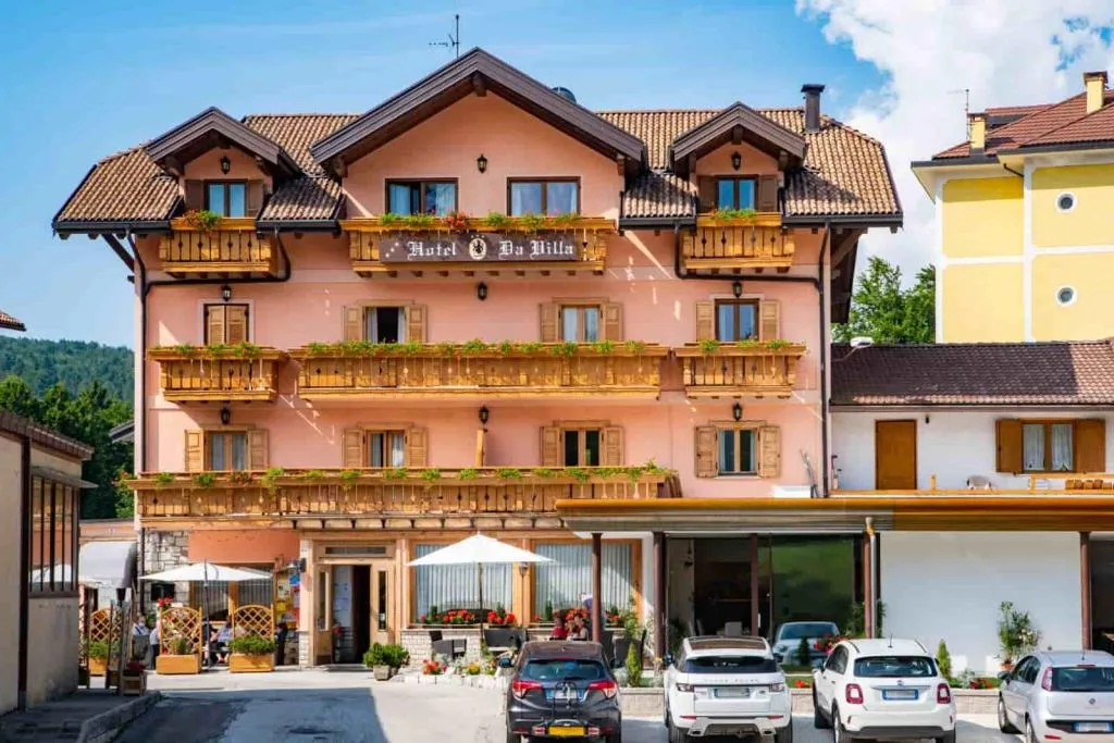 Facciata frontale dell'Hotel Da Villa con balconi fioriti e auto parcheggiate in estate