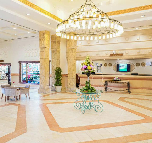 Ampia hall dell'hotel con lampadario, colonne in pietra e reception