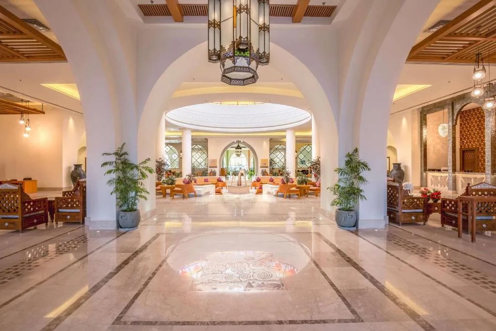 Elegante hall dell'hotel con archi, pavimento in marmo, lampadario decorativo e zone salotto