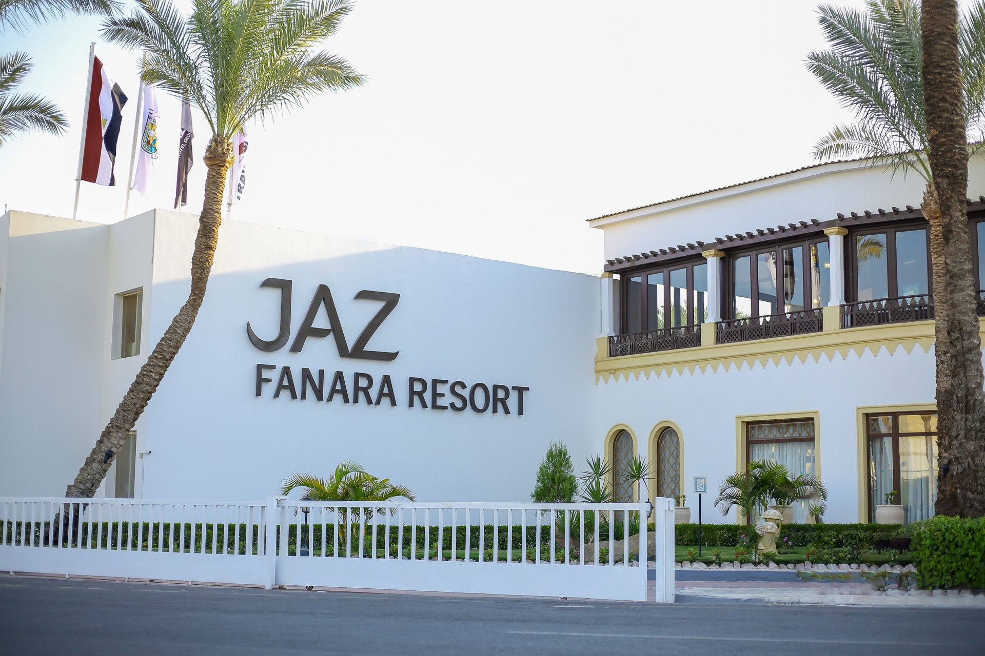 Ingresso del Jaz Fanara Resort con insegna, bandiere e palme
