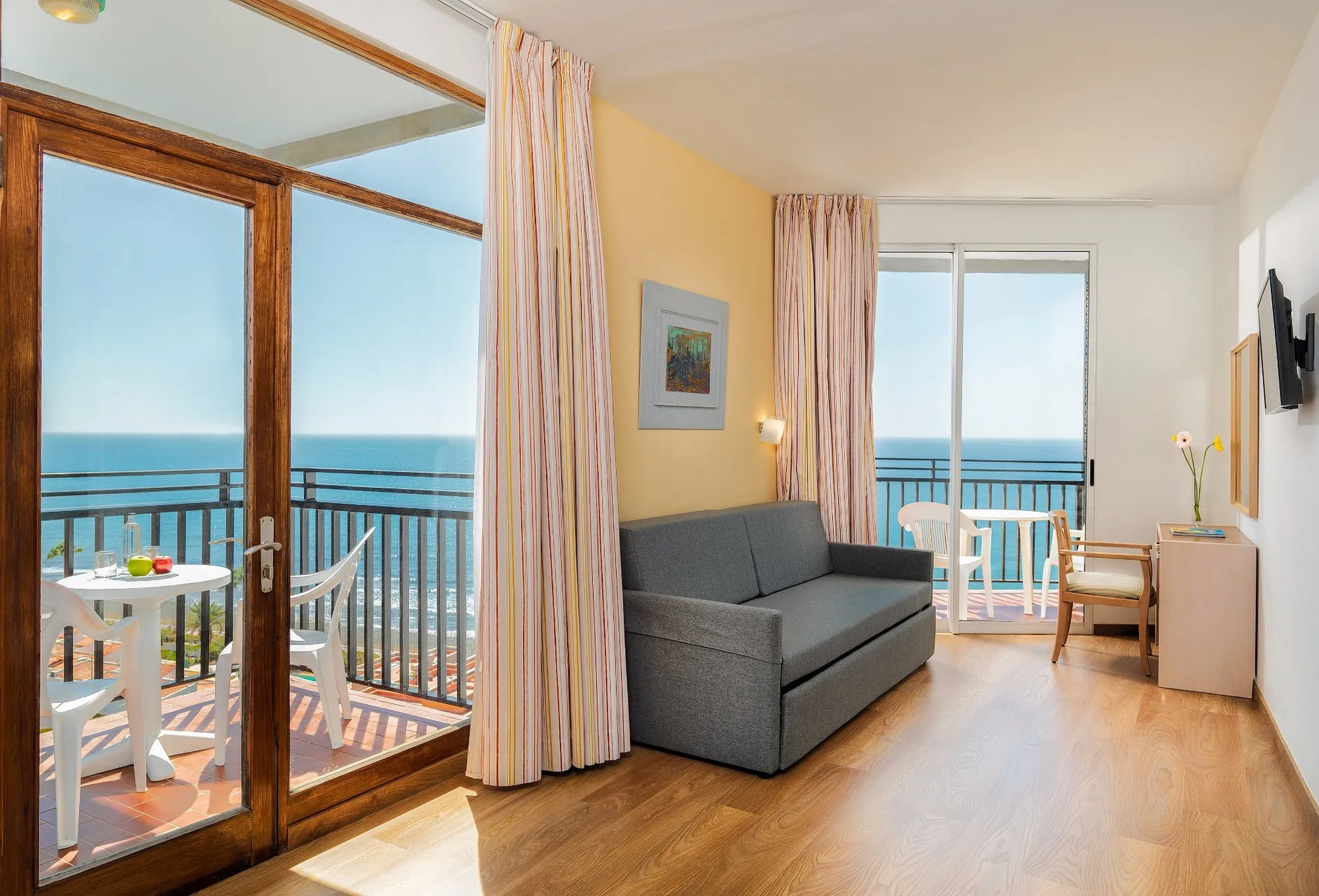 Soggiorno della camera con divano, tavolino e ampio balcone con vista mare