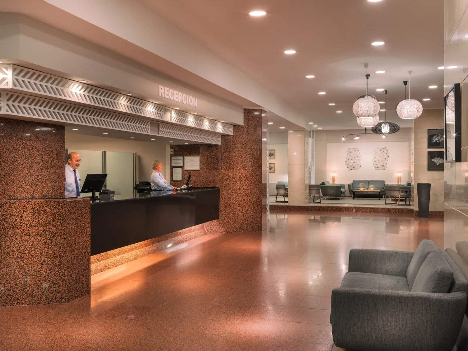 Reception dell'hotel con banco in pietra, area lounge e illuminazione soffusa